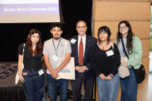 One man with four students stand in front of stage and screen.
