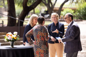 Three women and one man laugh together in botanical garden setting