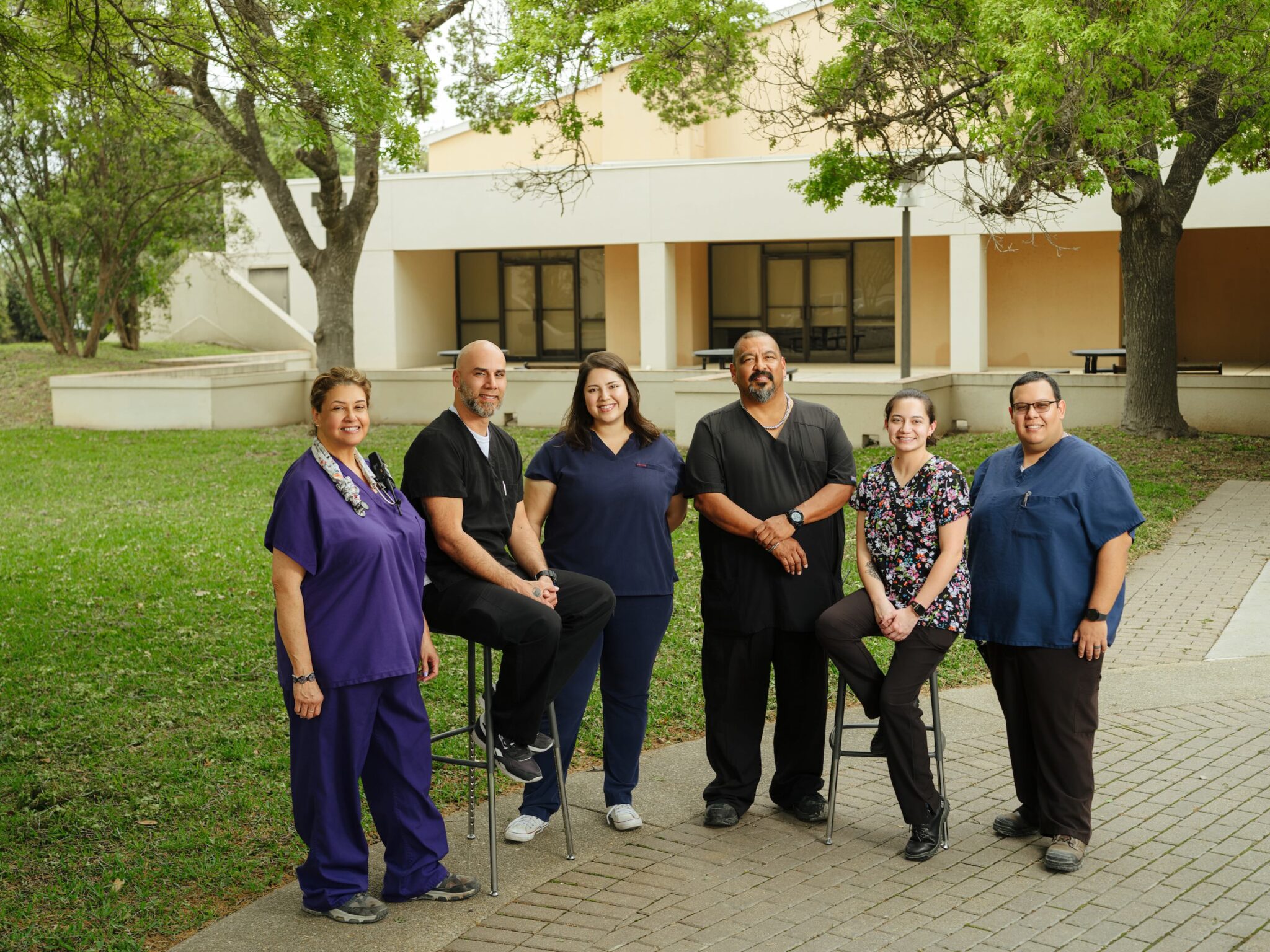 Group of people wearing scrubs are standing outside, looking at the camera