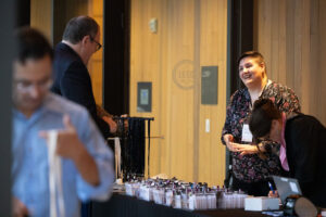 Person in floral shirt welcomes conference attendees at registration table