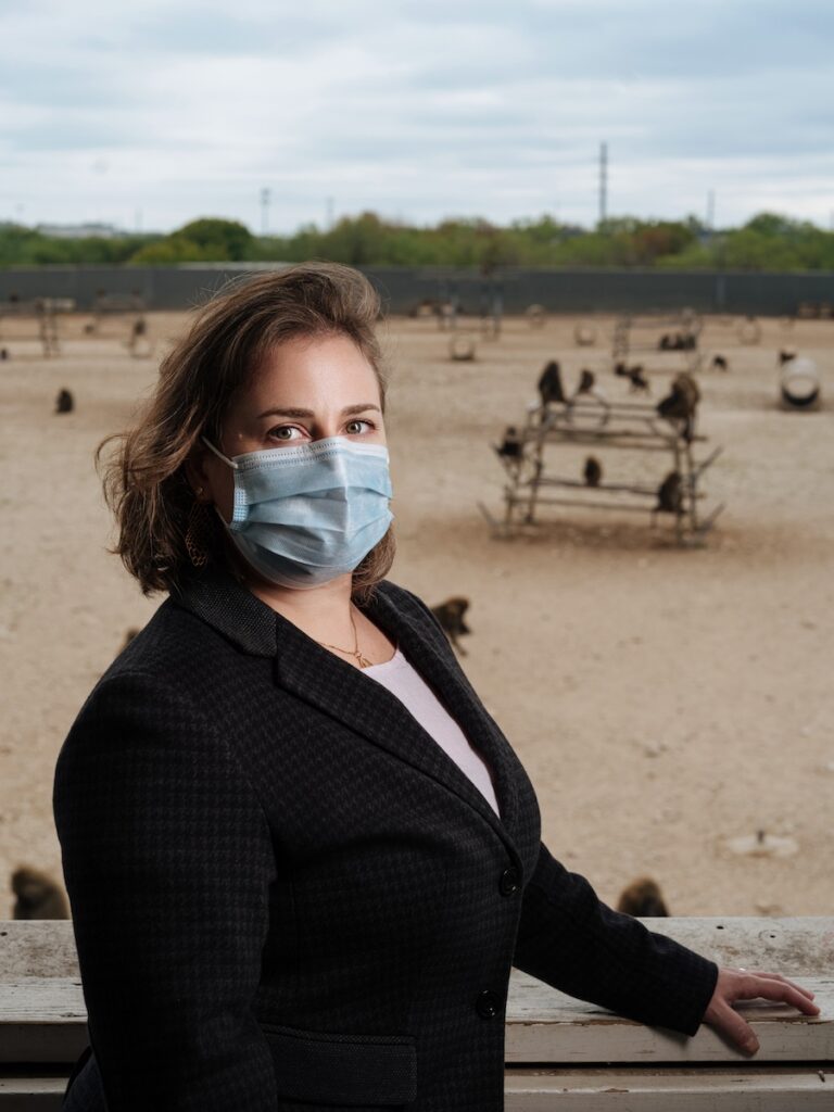 Woman wearing mask looking at camera, with baboons in background