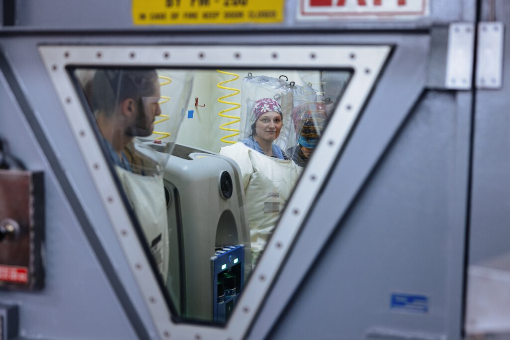 Through window photo of researchers in the BSL4 lab